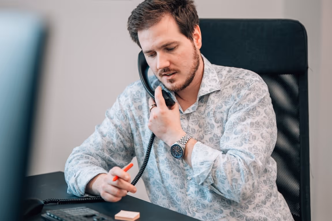 Mann telefoniert im Büro und macht Notizen
